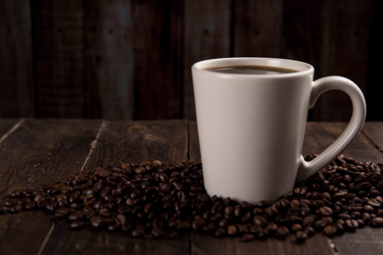 Cup of coffee surrounded by coffee beans